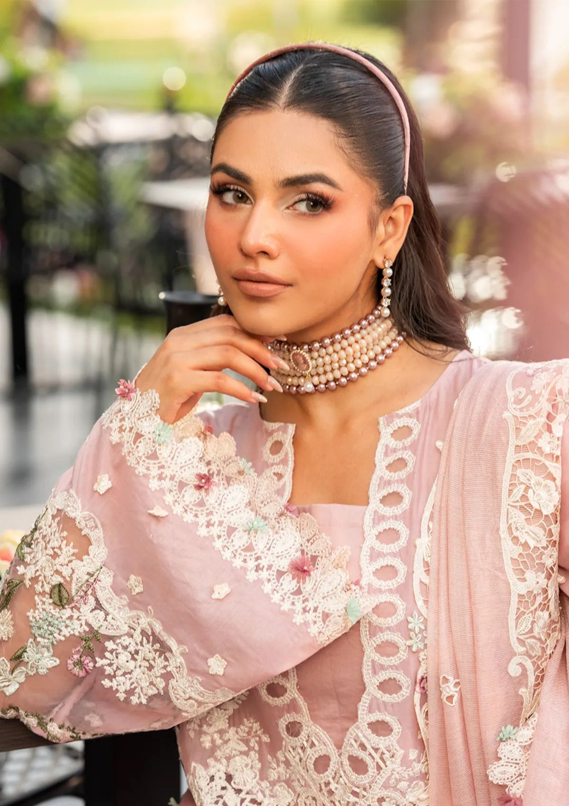 Woman wearing an elegant blush pink suit with wide-leg trousers featuring detailed cutwork."