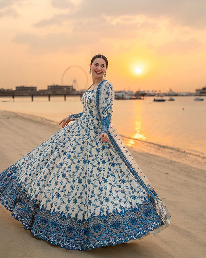 Model in a long white and blue embroidered pishwas maxi at the beach.