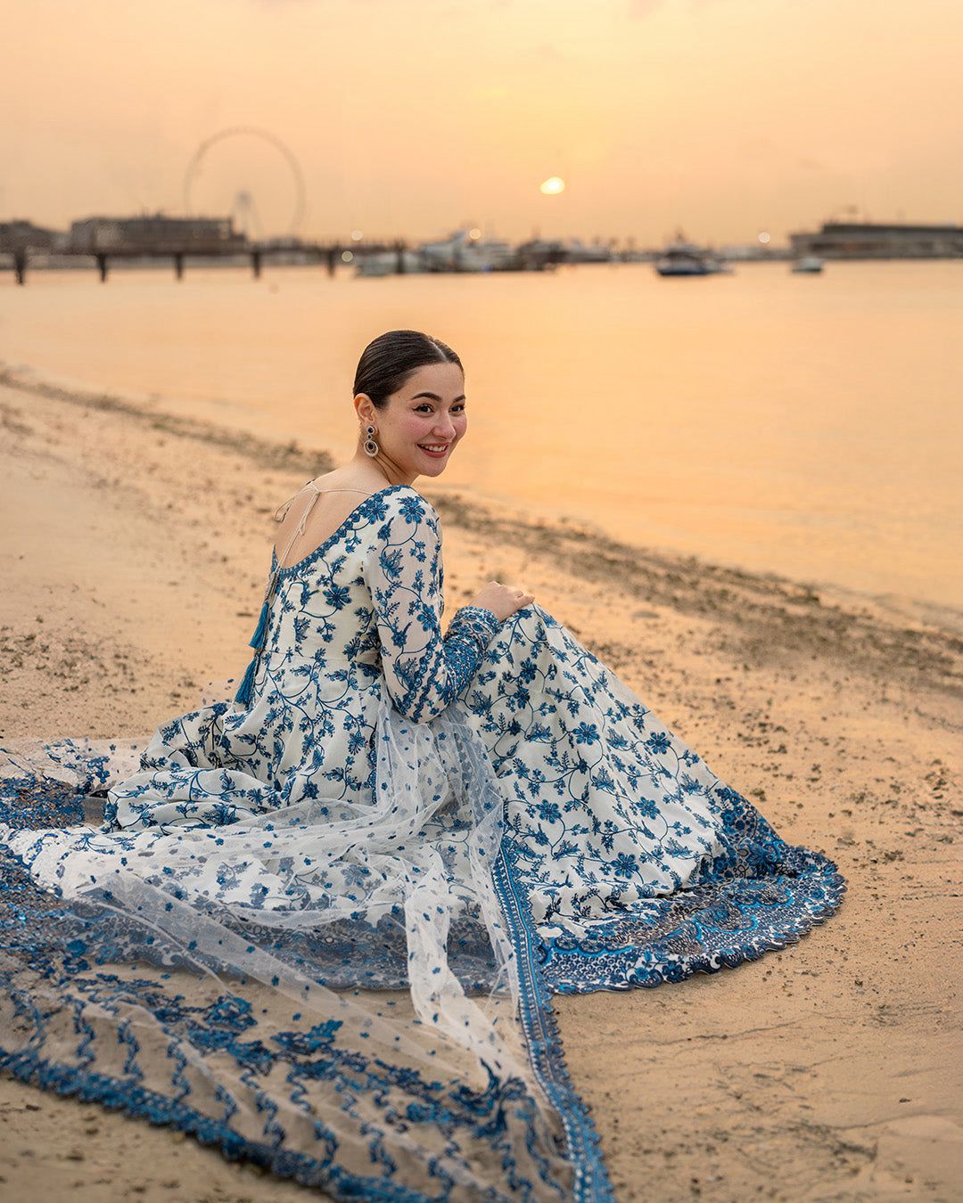 Full view of a luxury white flared dress with intricate blue floral threadwork.