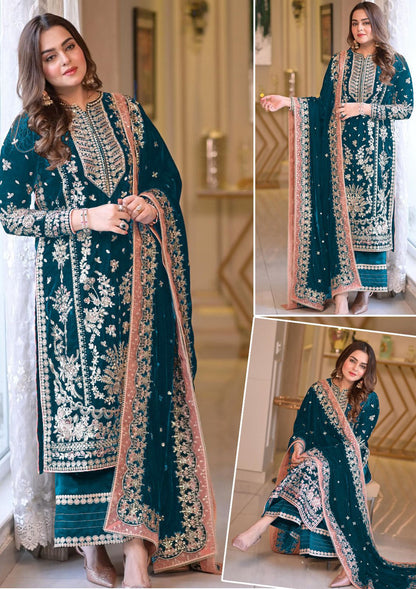 Model posing in a luxury teal velvet unstitched suit with heavy gold embroidery.