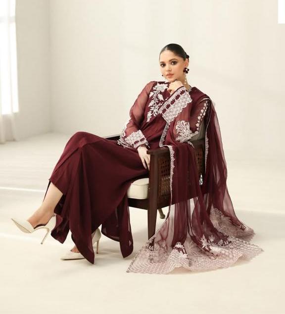 Model sitting in a maroon unstitched chiffon suit with white embroidery.