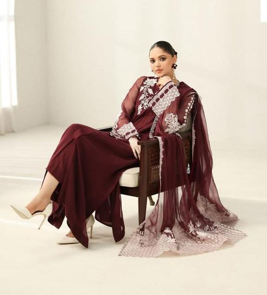 Model sitting in a maroon unstitched chiffon suit with white embroidery.